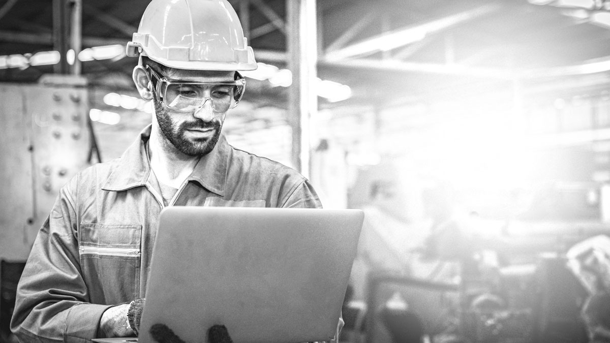 Confident engineer in blue jumpsuit holding laptop computer in a